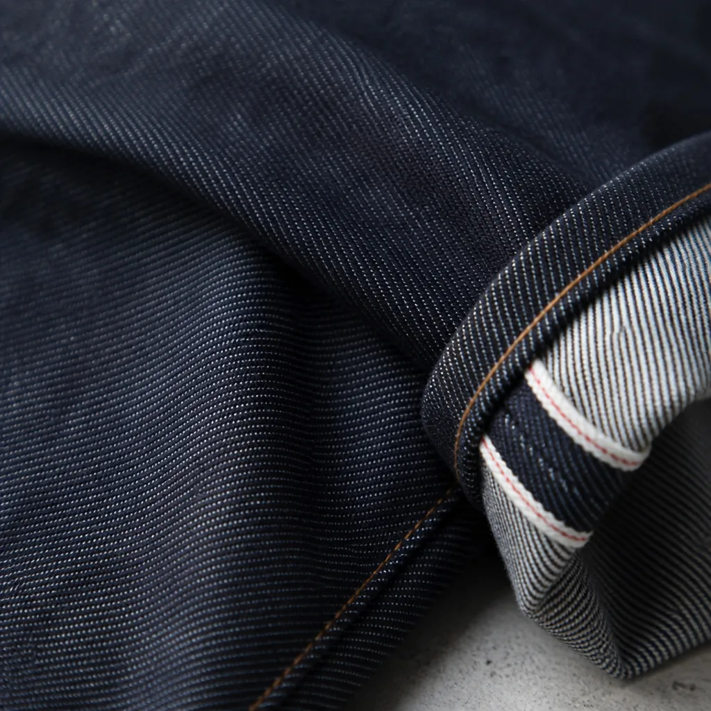 Primo piano di tessuto denim grezzo rigido e indaco scuro con trama twill diagonale visibile