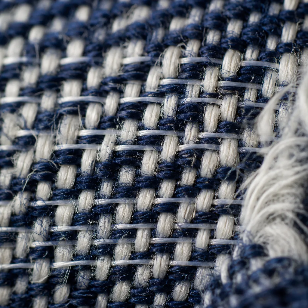 Primo piano della trama di un tessuto denim elastico che mostra sottili fili di elastan intrecciati tra i filati di cotone